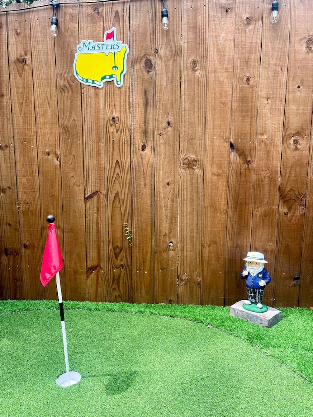 Une clôture en bois ornée d’un drapeau, d’un drapeau de golf et d’une figurine.