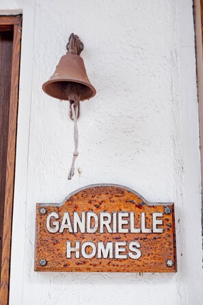 A weathered metal sign with the inscription 'GANDRIELLE HOMES' mounted on a white wall.