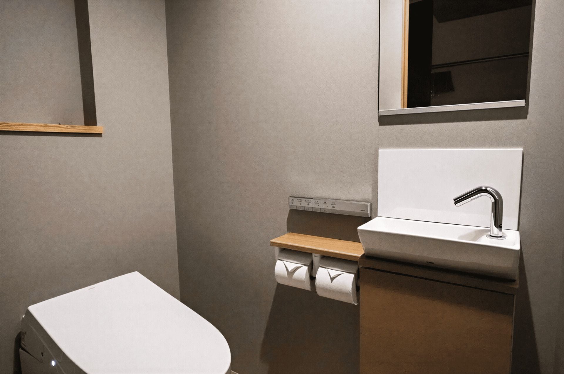 A bathroom with a toilet, a sink, and a towel dispenser.