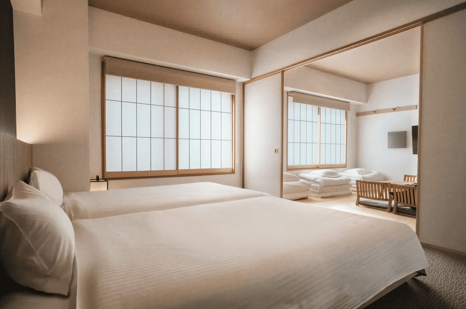 Habitación de hotel con una cama grande, zona de estar con una mesa y sillas, y un ventanal con vistas.