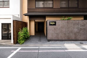 A modern building with a wooden fence, a sign reading 'OAKS.', and a paved entrance. - Oaks Vacation Club Kyoto Gojo (Kyoto)