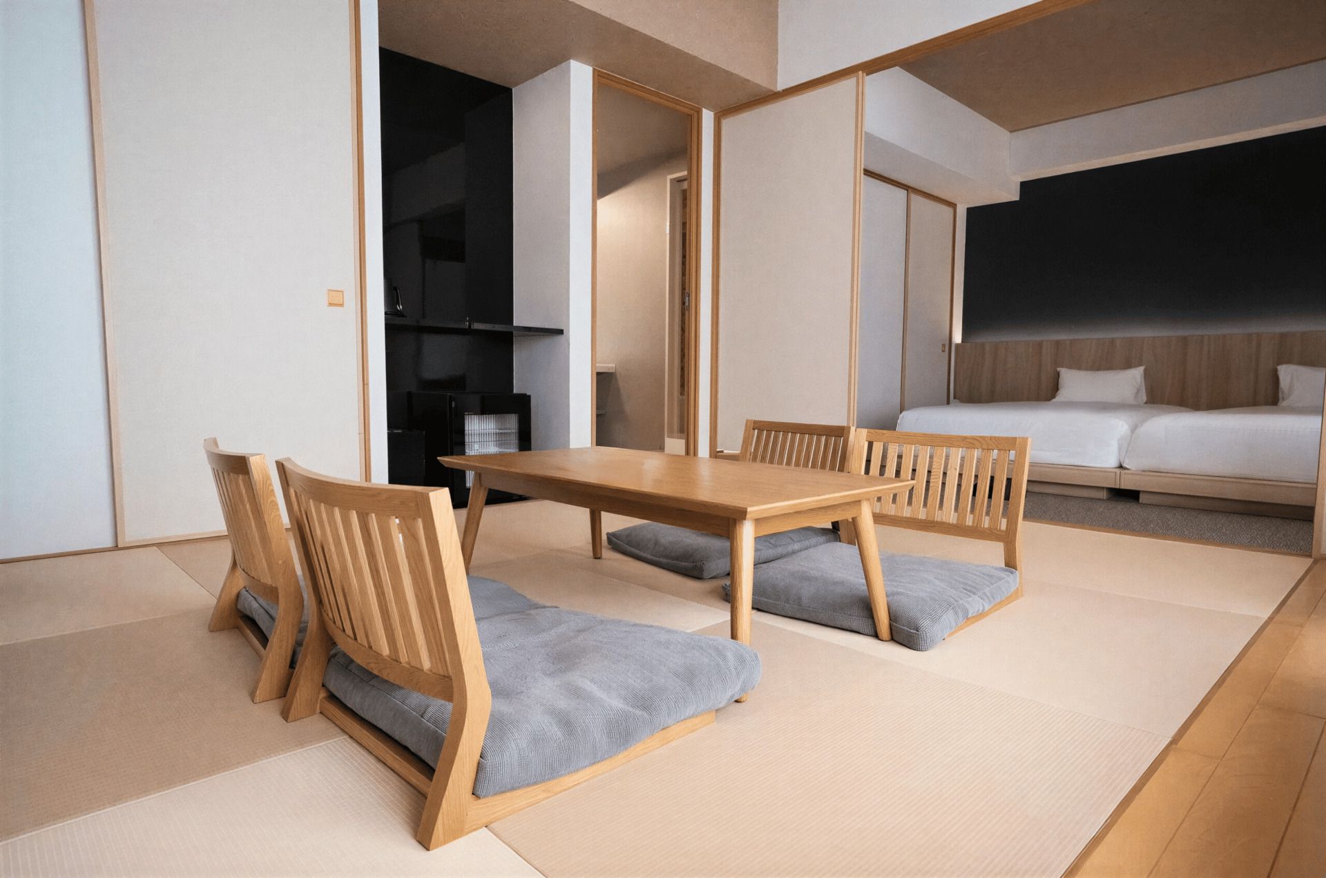 A room with a wooden dining table, two chairs, a bed, and a view of the outside.
