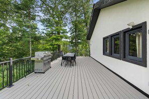 A deck with a grill, table, and chairs, surrounded by trees. - Twin Pines Lodge - Luxury Cabin, Kid Friendly (Catskill)