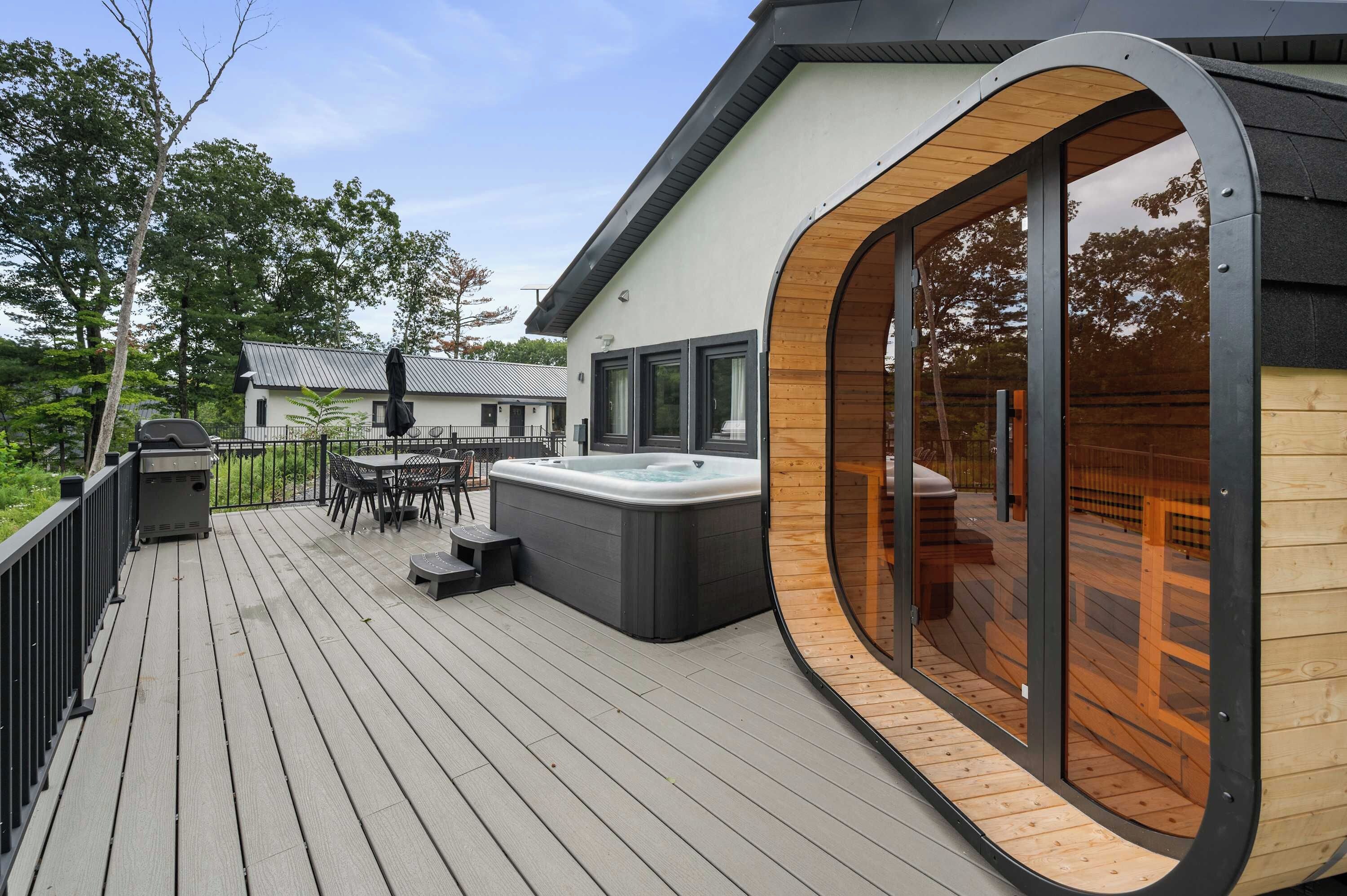 A modern outdoor deck with a hot tub, wooden deck flooring, and a glass-enclosed area.