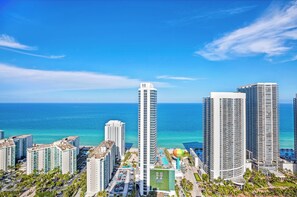 Um hotel alto com vista para o oceano, com várias varandas e área de piscina.