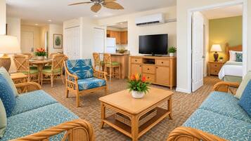 A hotel room with a dining area, kitchenette, and a television.