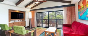 A living room with a flat-screen TV, wicker furniture, a red sofa, and a large sliding glass door leading to an outdoor deck.