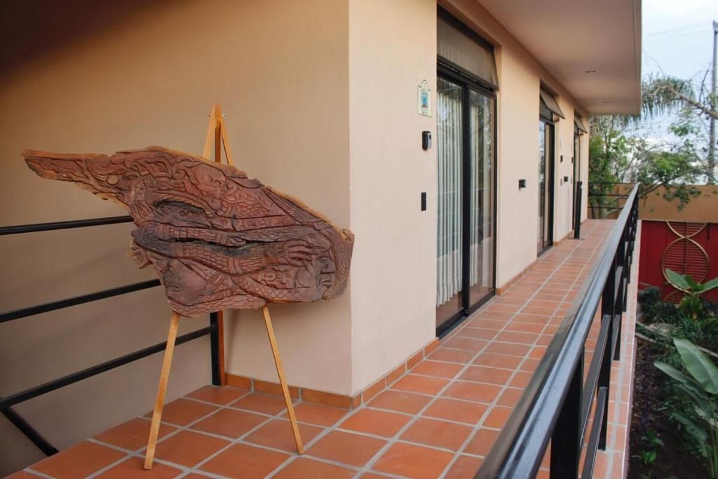 A corridor with a tiled floor, a wooden easel with a sculpture, and a door with a glass panel.