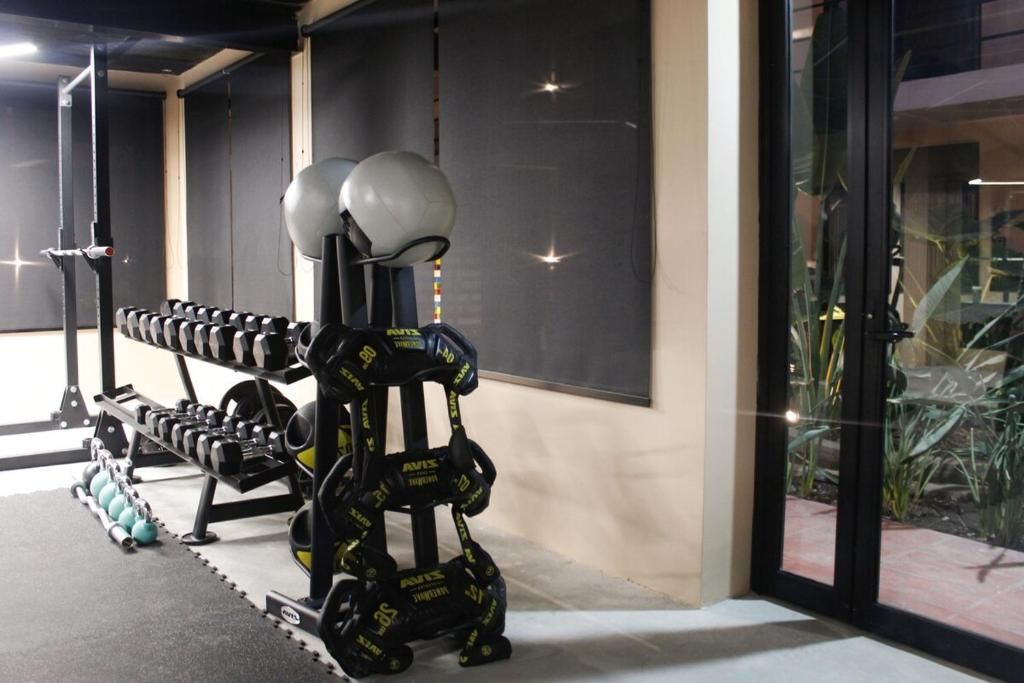 Un gimnasio con equipo de levantamiento de pesas, incluyendo mancuernas y una estructura para sentadillas.