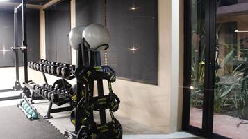 Un gimnasio con equipo de levantamiento de pesas, incluyendo mancuernas y una estructura para sentadillas.