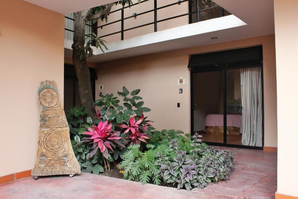 A room with a bed, a window, and a balcony with plants.