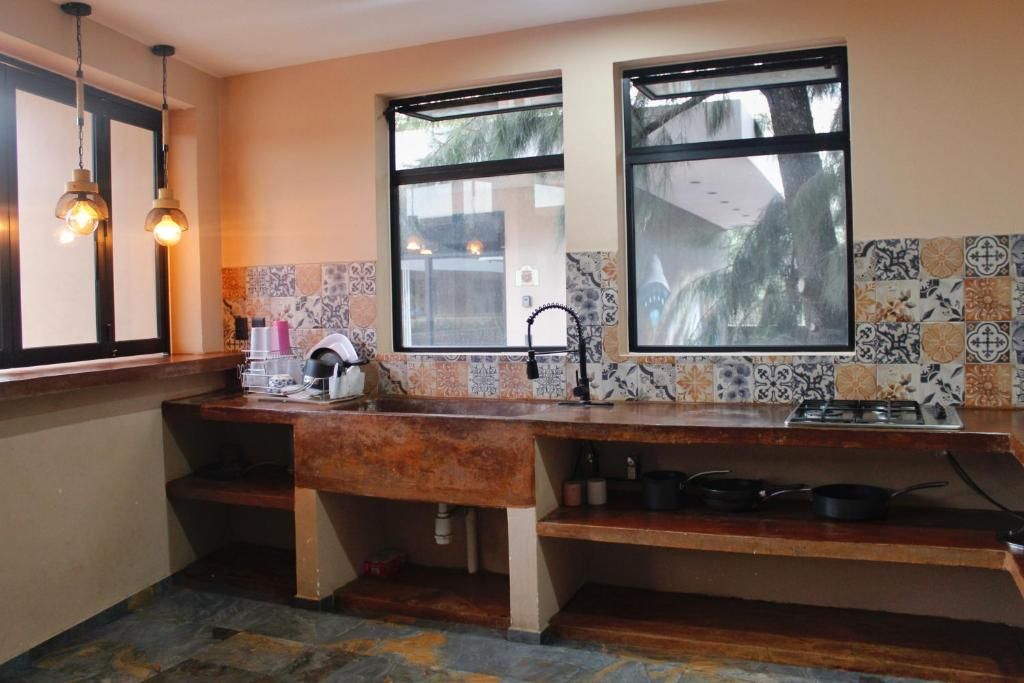 A kitchen with a wooden countertop, a gas stove, and a sink. There are two windows providing natural light.