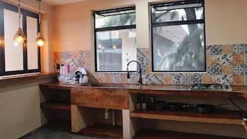 A kitchen with a wooden countertop, a gas stove, and a sink. There are two windows providing natural light.