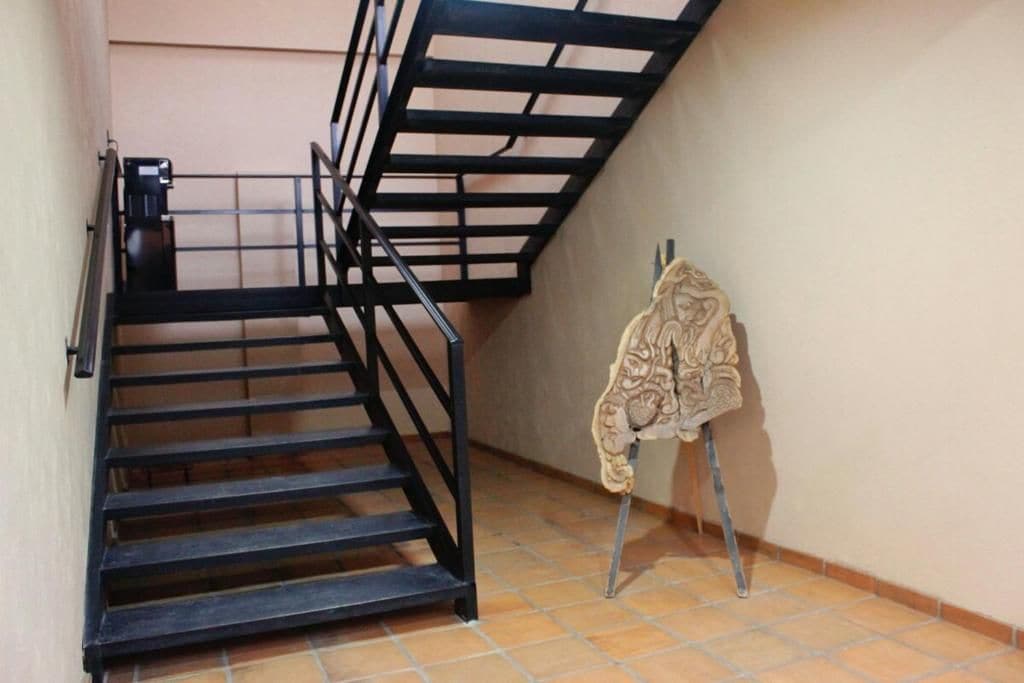 A staircase with black railings and a patterned coat hanging on a stand.