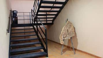 A staircase with black railings and a patterned coat hanging on a stand.