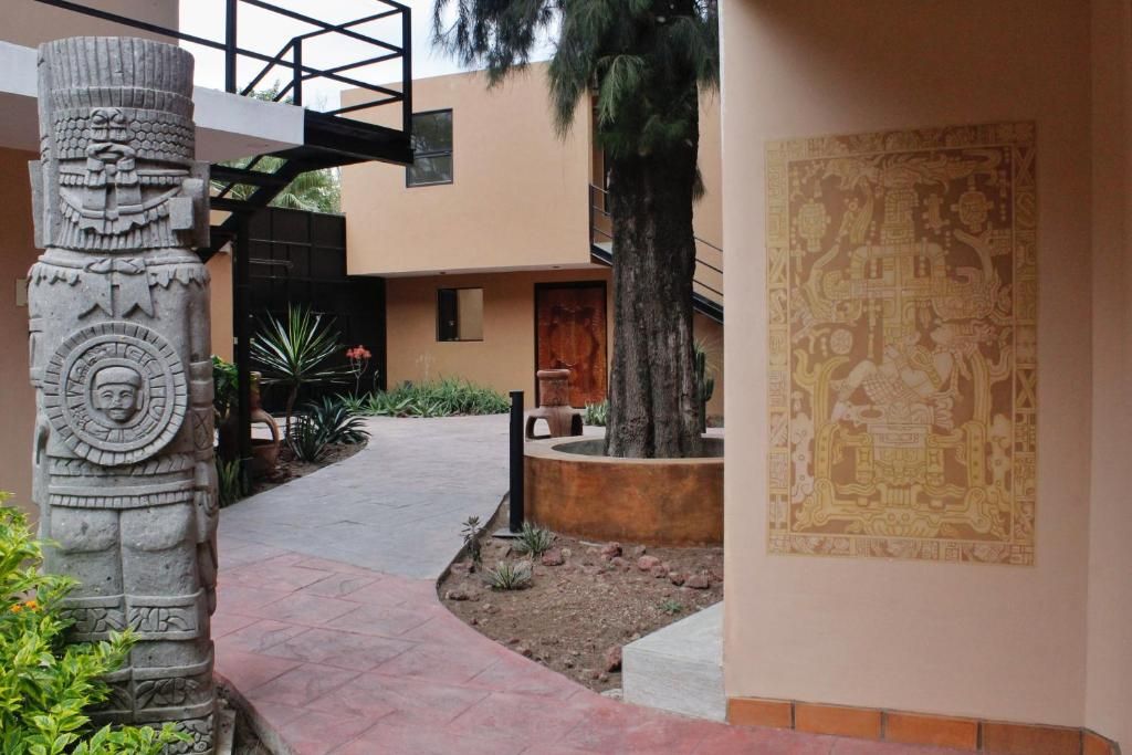 Un patio con un pilar de piedra, un mural y una palmera.