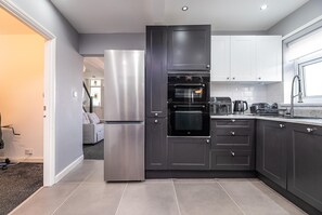 Eine moderne Küche mit Backofen, Kühlschrank und Kaffeemaschine.