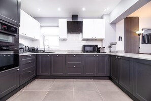 A modern kitchen with dark cabinets, a microwave, a toaster, and a sink. - Spacious 4 Bed Detatched Nottingham House I Sleeps 11 I Parking for 3 I Garden (Nottingham)