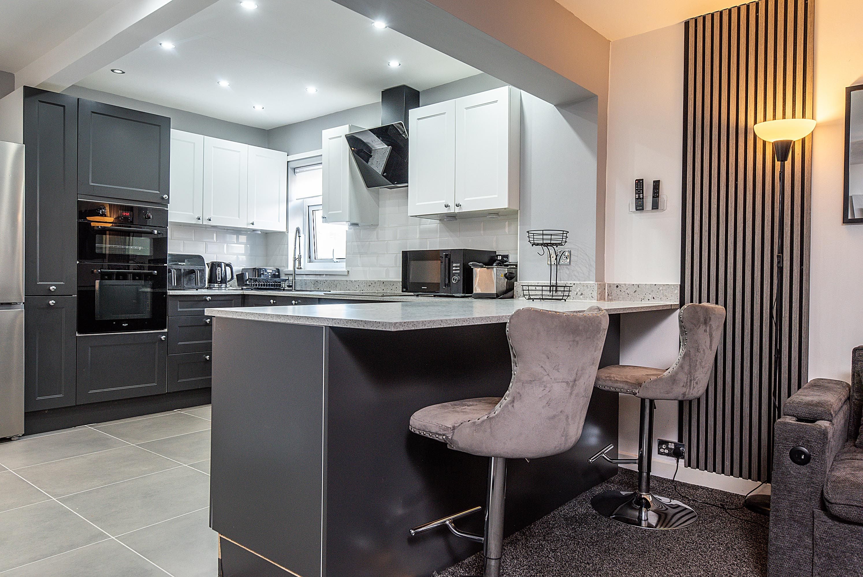 A modern kitchen with a central island, bar stools, and a built-in oven.