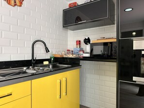 A modern kitchen with a black countertop, yellow cabinets, and a stainless steel sink. - Apartamento Texas Life - Ole Solutions (Jerez de la Frontera)