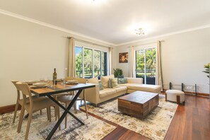 Ein geräumiges Wohnzimmer mit Essbereich, großen Fenstern und einer gemütlichen Sitzecke.