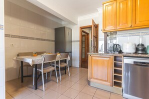 A kitchen with a dining table, chairs, a refrigerator, a dishwasher, and wooden cabinets. - Musa d Ajuda by Atlantic Holiday (Funchal)