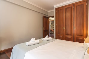 Ein Hotelzimmer mit zwei Betten, einem Holzschrank und einem durch eine geöffnete Tür einsehbaren Badezimmer.
