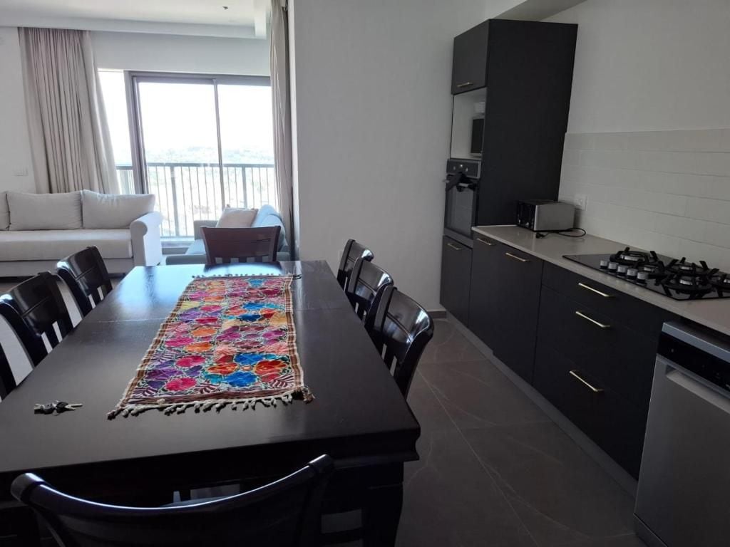 A modern kitchen with dark cabinets, a gas stove, and a dining area with a table and chairs.