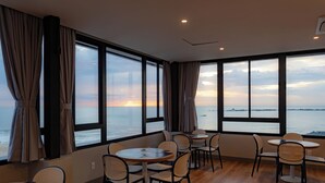 A room with large windows, wooden flooring, and multiple tables and chairs. - Bella Vista By Candeias (Barra Velha)