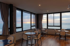 A room with large windows, wooden flooring, and multiple tables and chairs. - Bella Vista By Candeias (Barra Velha)