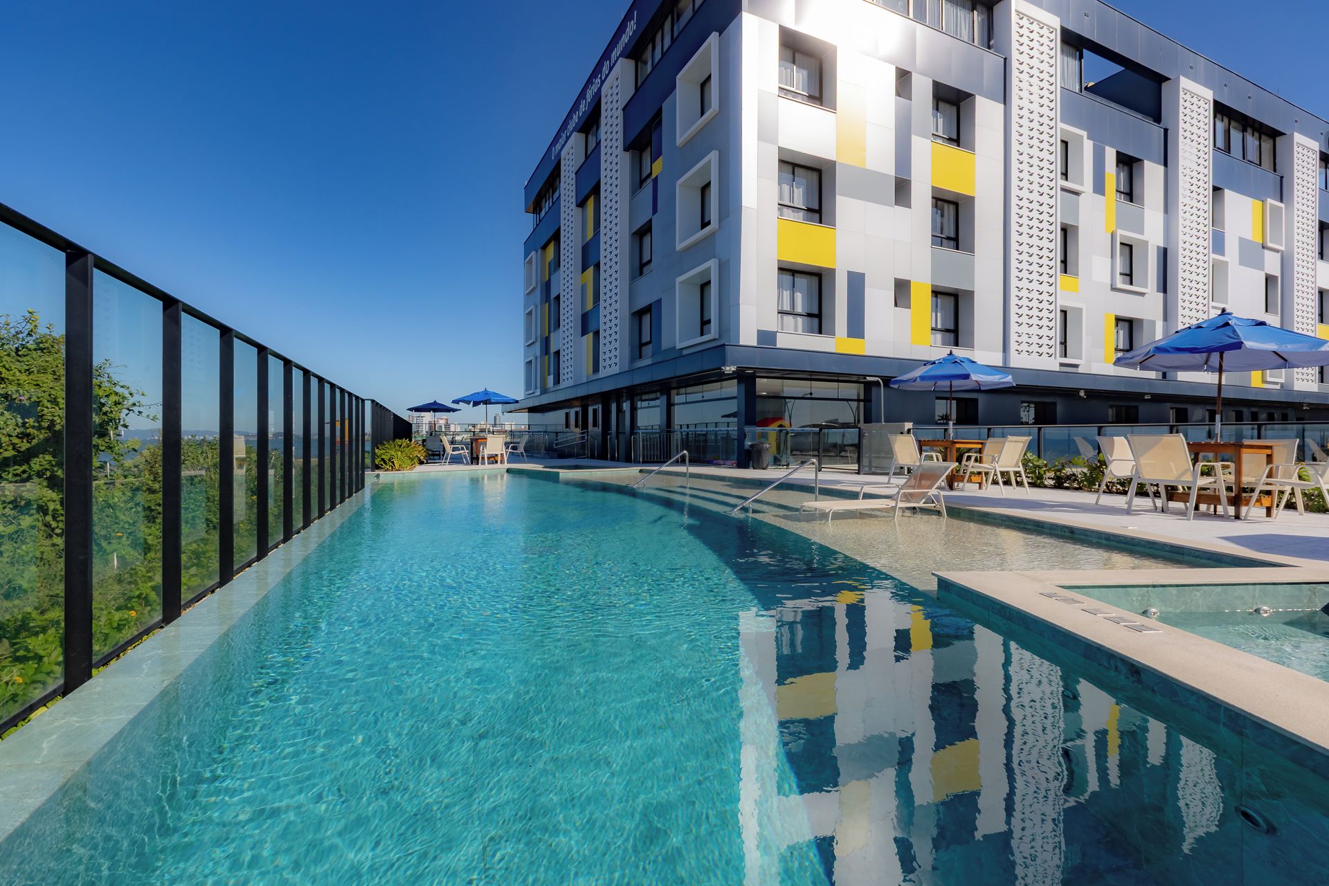 Un hotel moderno con piscina, mobiliario exterior y vistas a la ciudad.