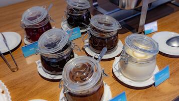 Una exhibición de diversos alimentos en frascos de vidrio con etiquetas, dispuestos sobre una mesa de madera.