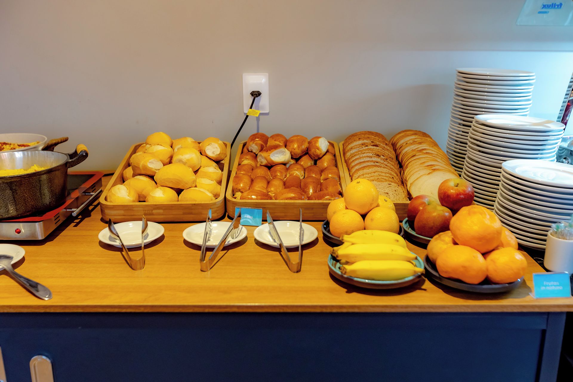 Un bufé con diversos alimentos, como pan, pasteles, frutas y una olla de comida en una estufa.