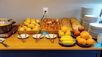Un bufé con diversos alimentos, como pan, pasteles, frutas y una olla de comida en una estufa.