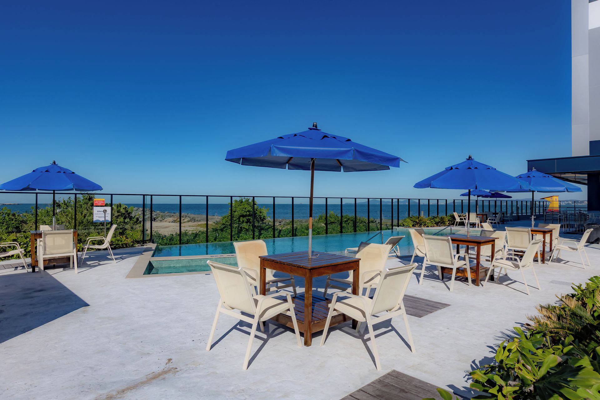 Un espace aménagé au bord de la piscine, avec des chaises longues et des parasols, donnant sur une étendue d’eau.