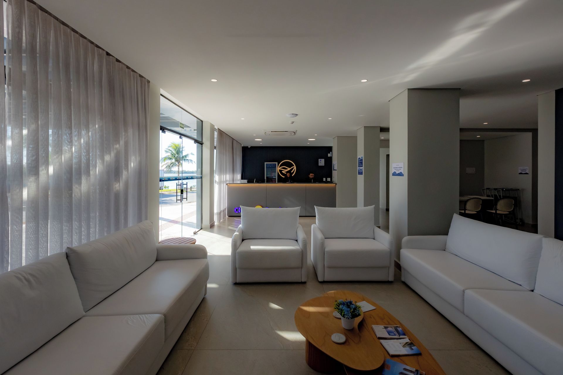 Un moderno vestíbulo de hotel con un mostrador de recepción, zona de estar y vistas al exterior.