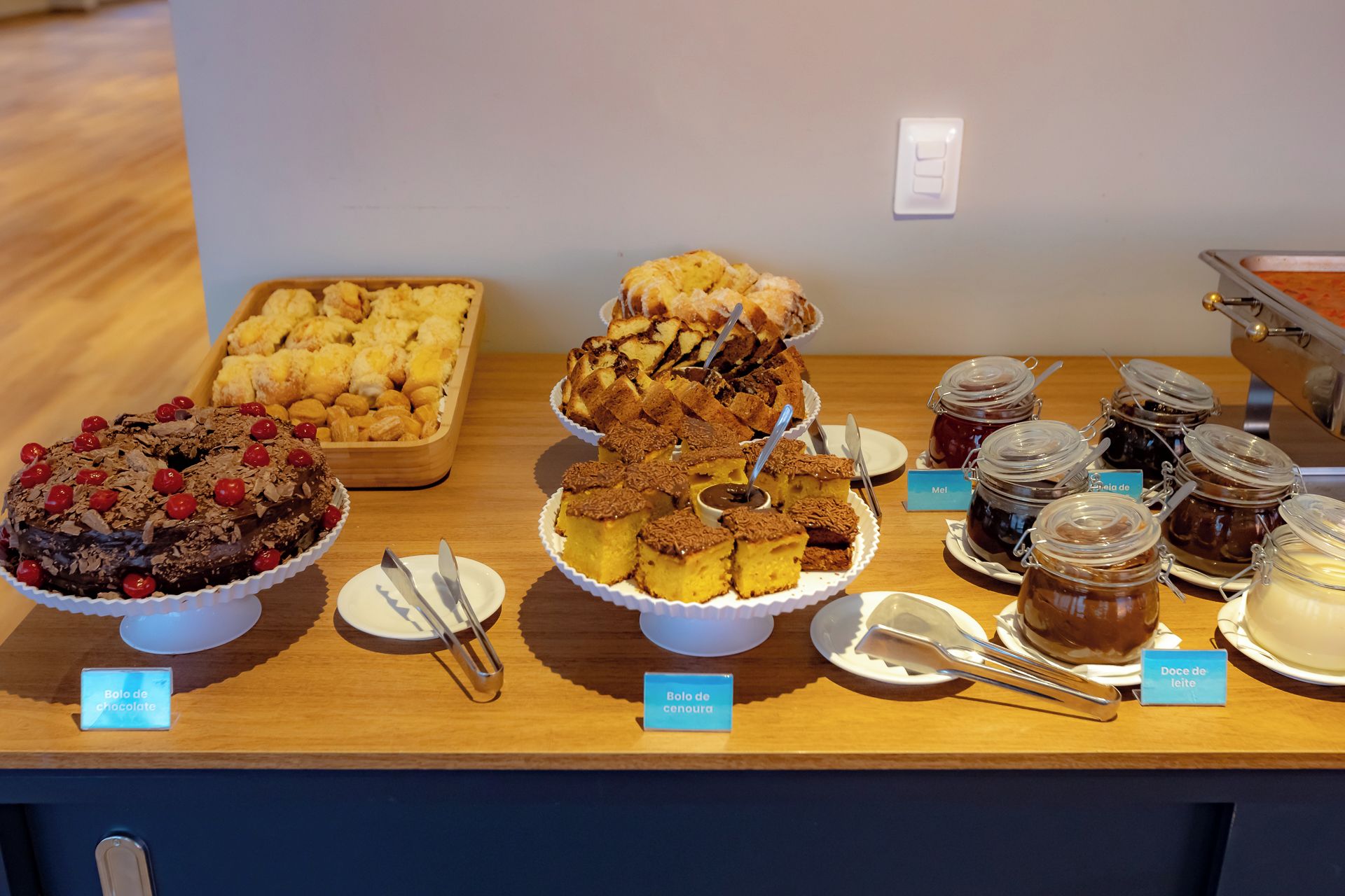 A buffet table with various desserts and spreads, including chocolate cake, lemon bars, and jams.
