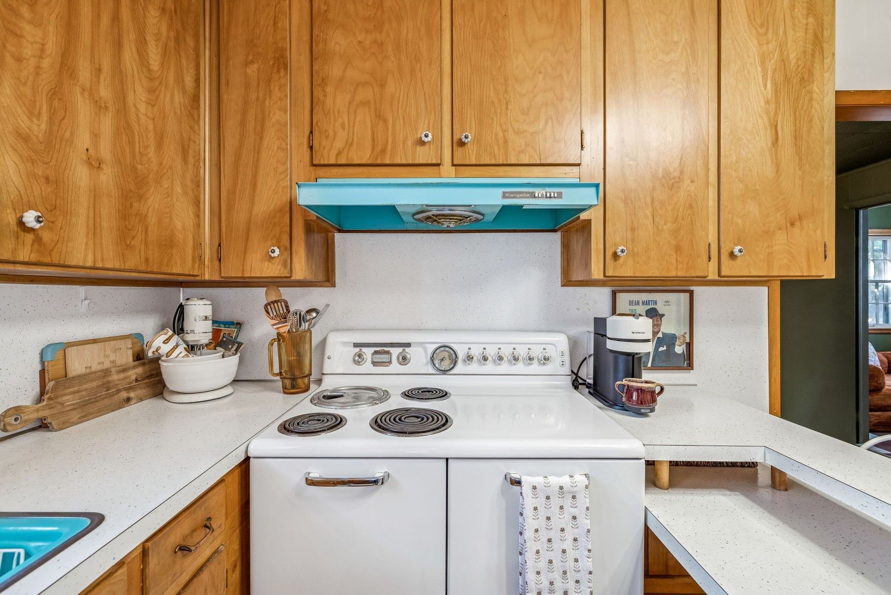 A kitchen with wooden cabinets, a white stove, and a coffee maker.