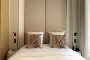 A hotel room with a large bed, two pillows, a nightstand, and a window with curtains. - Luxurious Suite - AC- 2P- Madeleine/saint Honore (Paris)