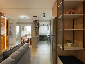A modern kitchen with a built-in refrigerator, wooden cabinets, and a dining area with a sofa and chairs. - Solarium Beach Club -Apartamento T1.602 (Itapoá)