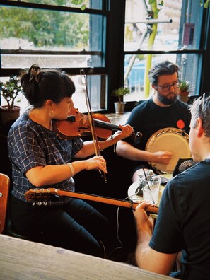 Una persona tocando el violín en una mesa, mientras otra persona sostiene un tambor.