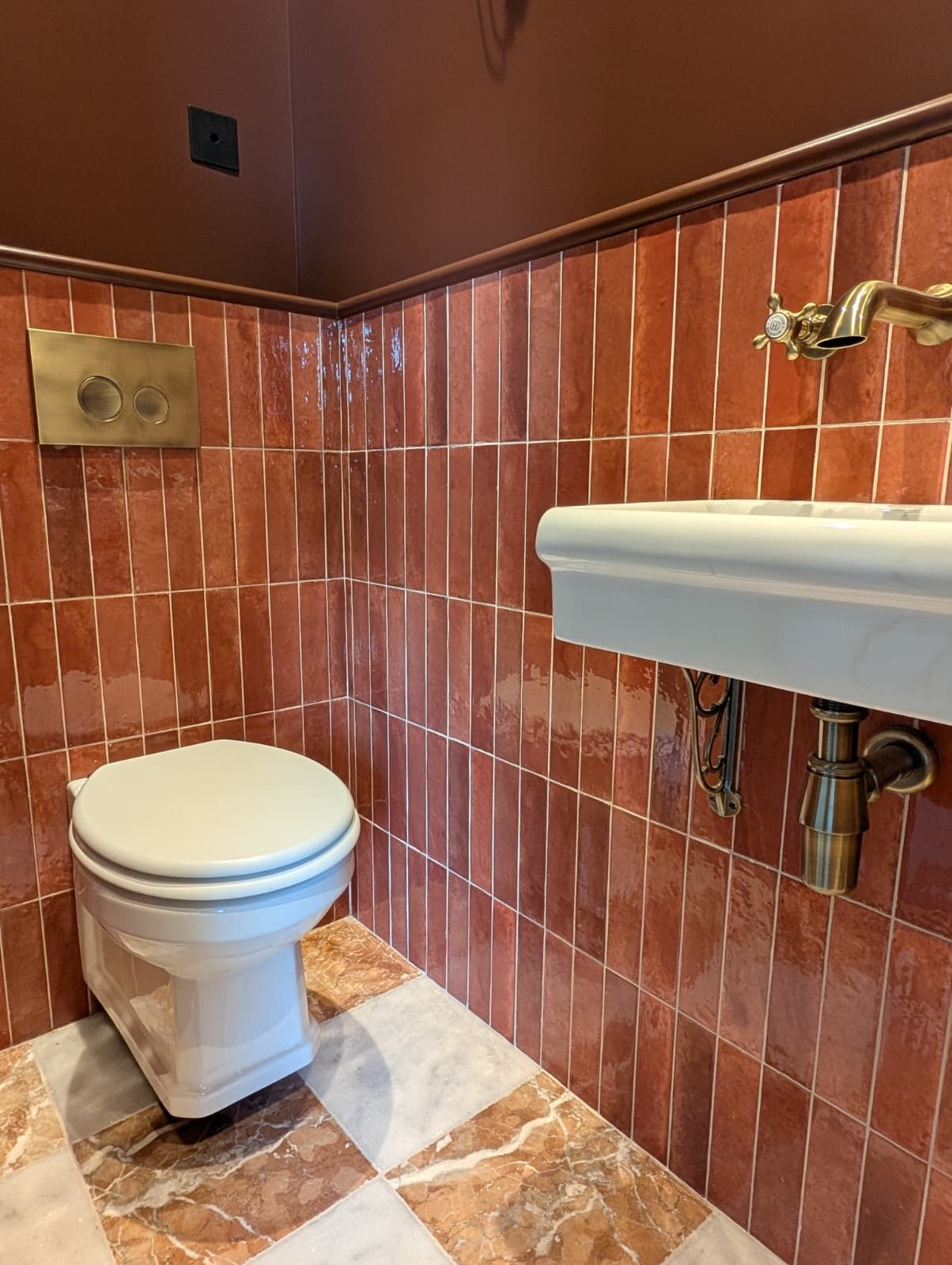 A bathroom with a toilet, a sink, and a wall-mounted faucet.