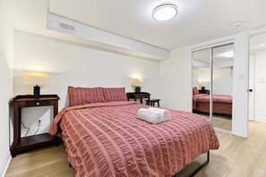 Een hotelkamer met een bed, nachtkastjes, lampen, een spiegel en een schuifdeur.