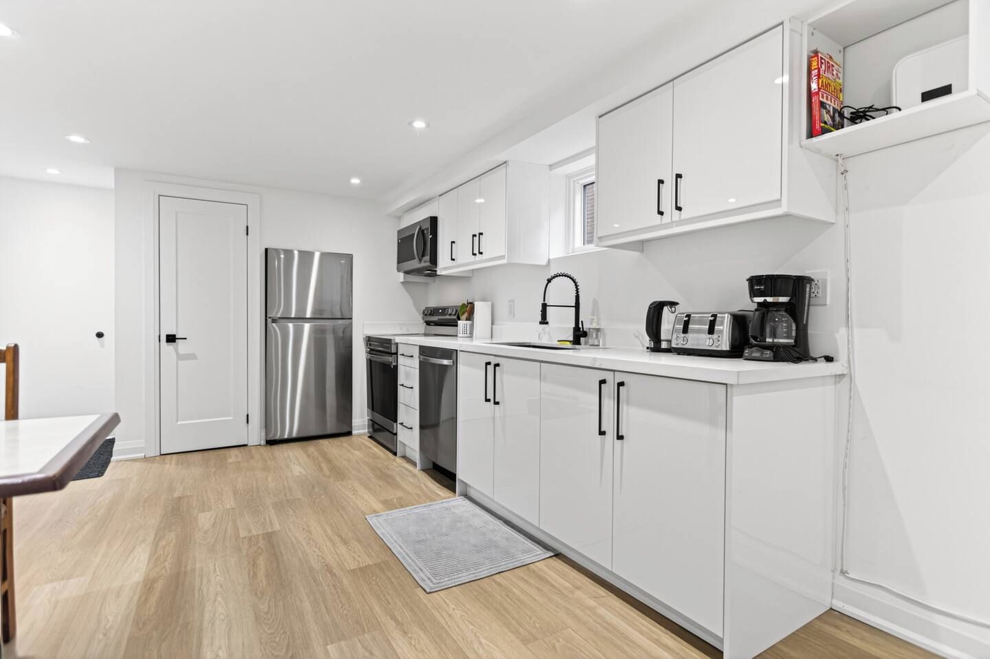 A modern kitchen with white cabinetry, stainless steel appliances, and a breakfast bar.