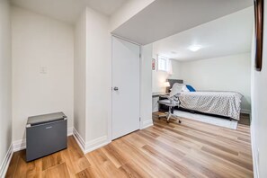 Een slaapkamer met een bed, bureau en stoel.