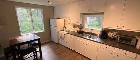 A kitchen with white cabinets, a stove, a sink, and a dining table with chairs.