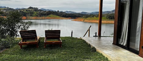 Un edificio moderno con puerta de vidrio que da a una terraza con vistas a un lago.