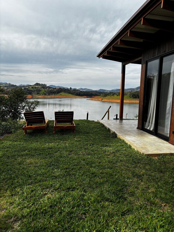 Un edificio moderno con puerta de vidrio que da a una terraza con vistas a un lago.