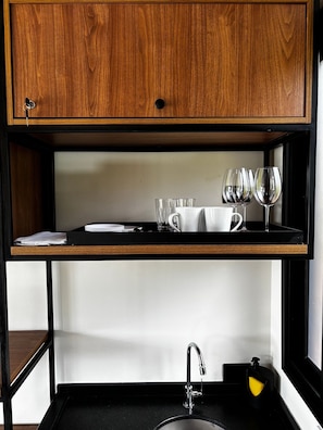 Un área de cocina con un armario de madera sobre una encimera negra, un lavabo con grifo y dispensador de jabón.