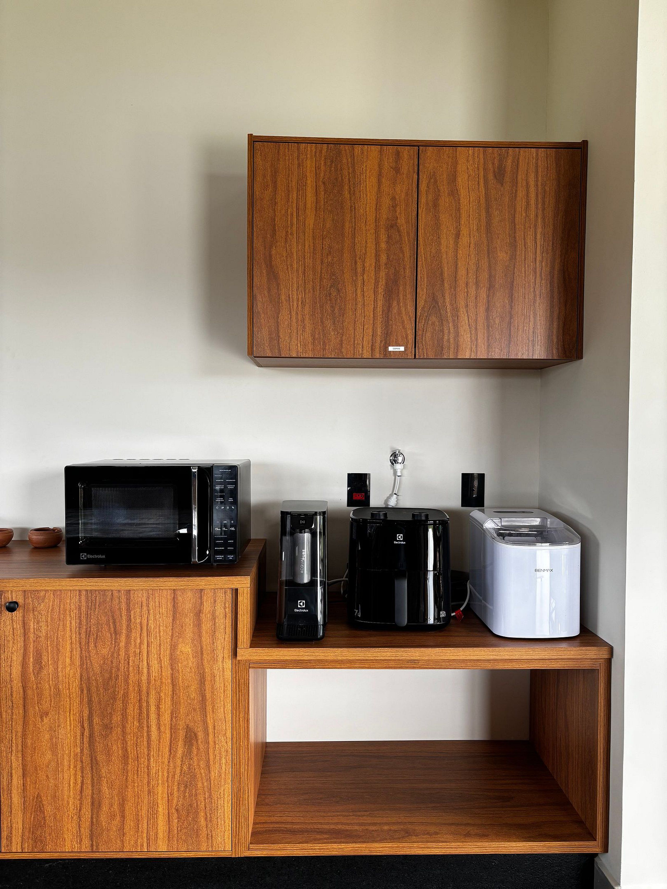 Una kitchenette con microondas, cafetera y tostadora sobre una encimera de madera.